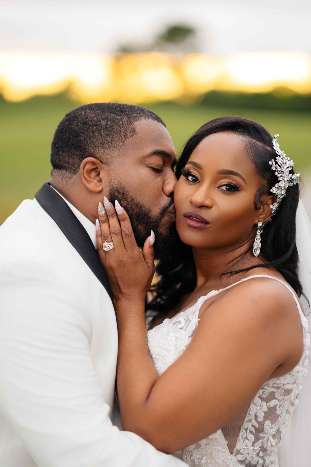 A romantic couple shares intimate moments in their wedding attire during an outdoor photoshoot at sunset.