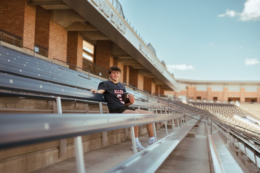 Empty stadium bleachers with rows of silver aluminum seating extend into the distance on a sunny day.