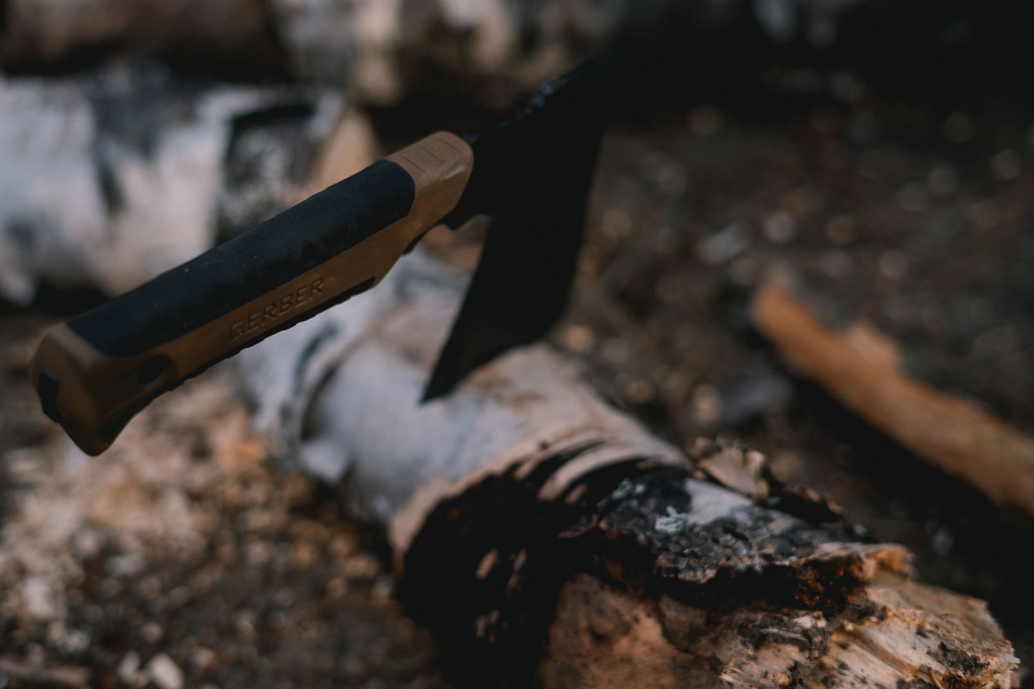 Gerber hatchet embedded in a wooden log, showcasing its durability and rugged design for outdoor use.