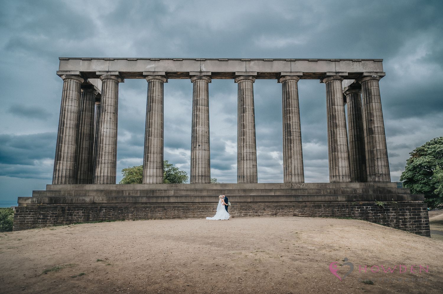 Ancient Greek-style stone columns forming the National Monument on Calton Hill in Edinburgh against a moody cloudy sky.