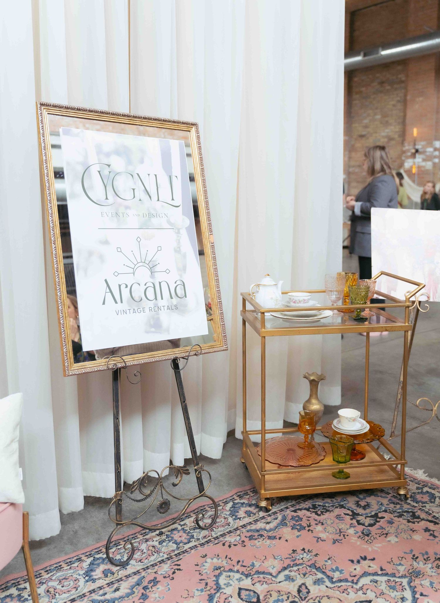Elegant gold-framed signage and bar cart display against white curtain backdrop at upscale event. At Fairlie, Chicago