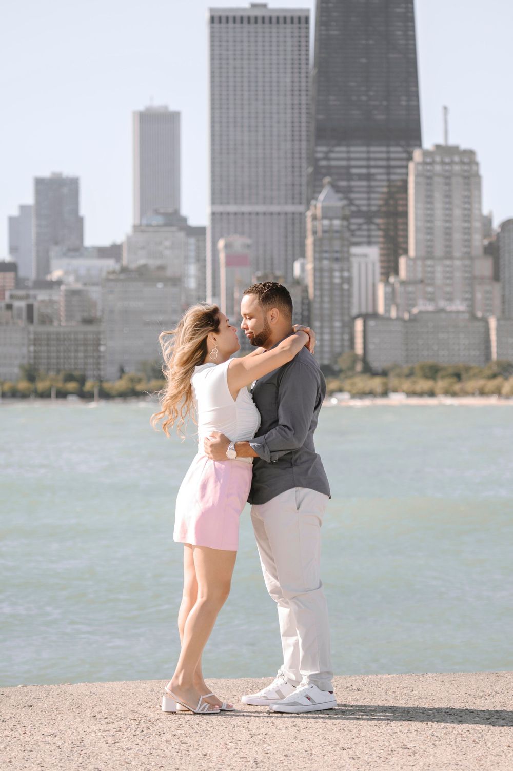 Romantic couple embracing with Chicago skyline in background along Lake Michigan shore.