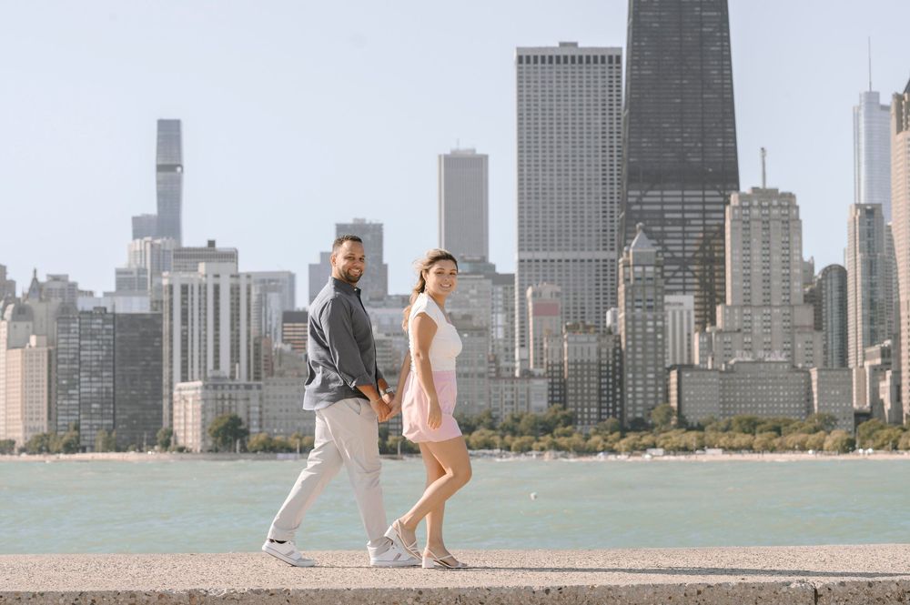 A romantic walk by Lake Michigan features a couple against Chicago's iconic downtown skyscrapers and waterfront.