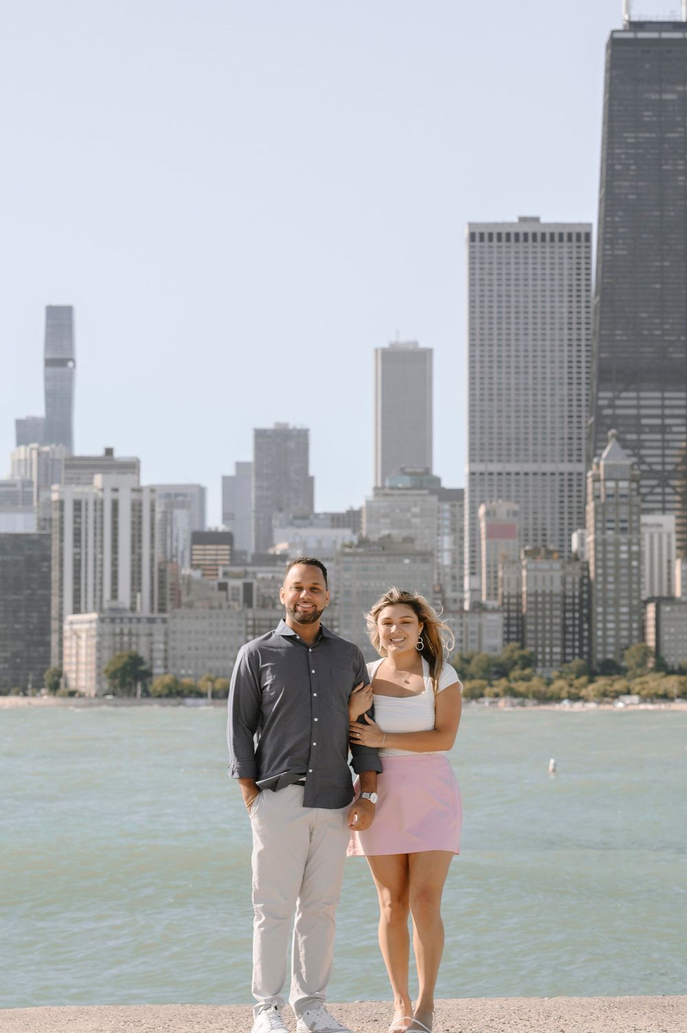 A couple poses together at Lake Michigan's shore with Chicago's magnificent downtown skyline in the background.