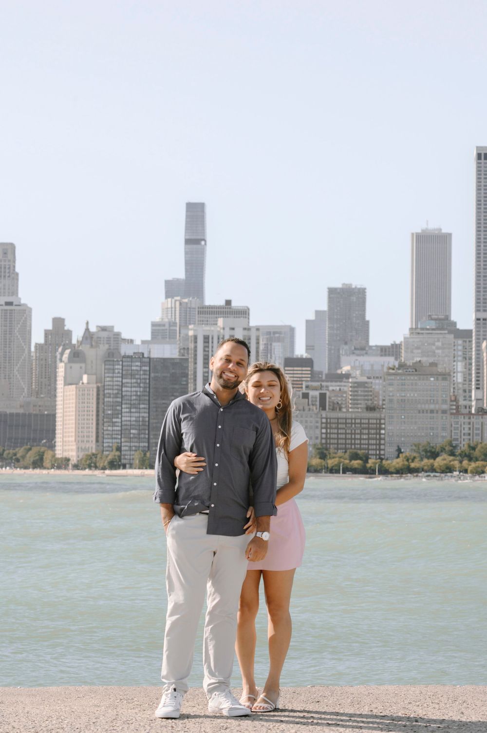 A couple poses together by the lakefront with Chicago's iconic skyline in the background.