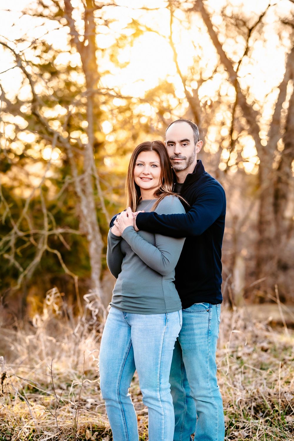 A couple embraces in a warm golden sunset among autumn trees with beautiful bokeh lighting.