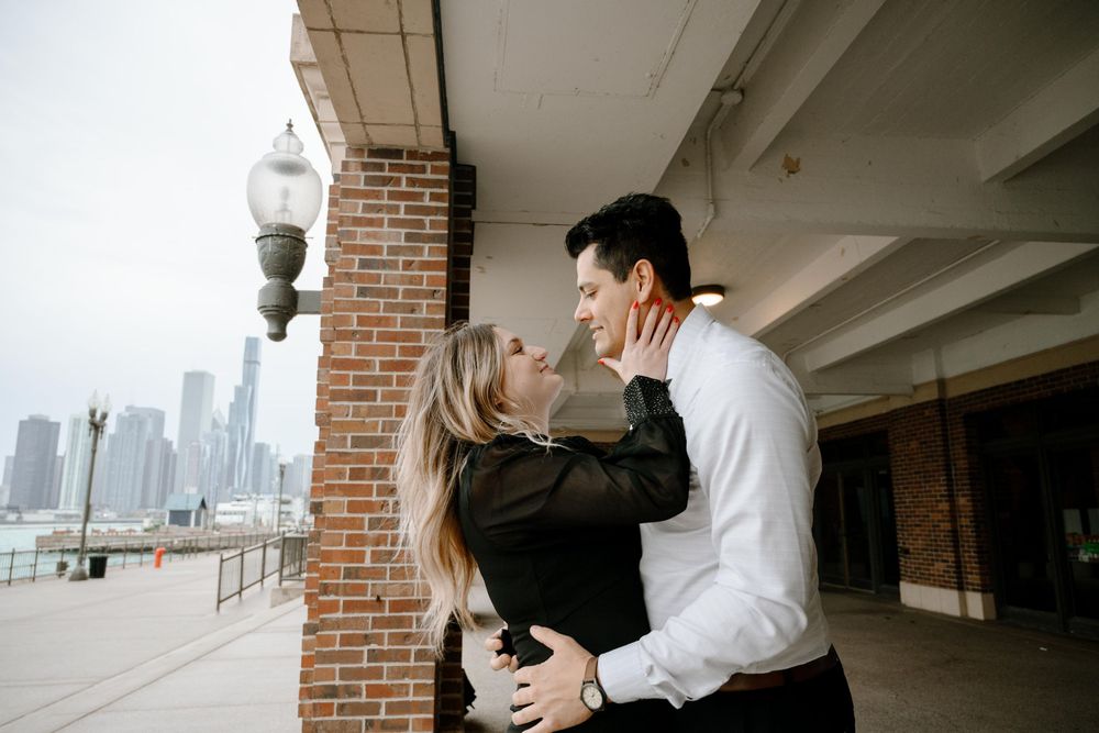 An intimate moment between a couple along a brick columned walkway with city skyscrapers in the background.