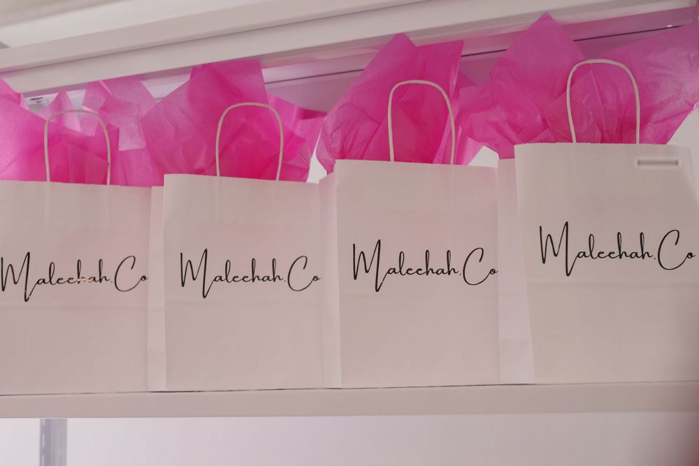 Pink balloon decorations and branded signage displayed along a white wall.