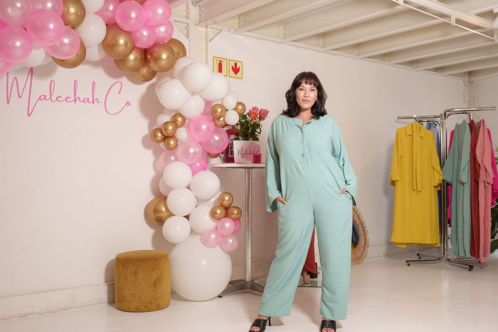 Fashion retail space decorated with pink and gold balloons displaying colorful clothing.