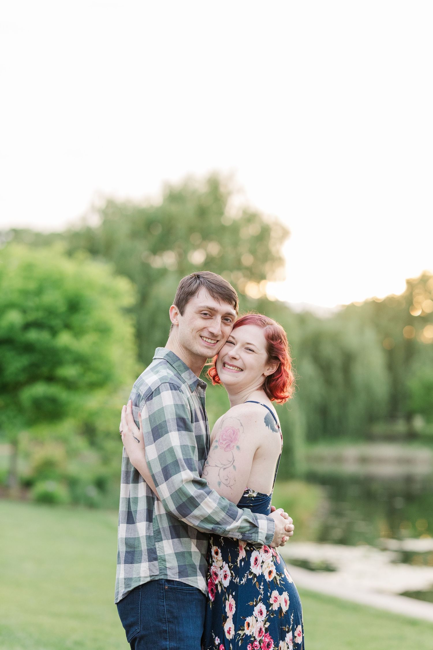 A couple embraces and laughs together in a romantic outdoor garden setting with a pond and greenery in the background at Cantigny Park