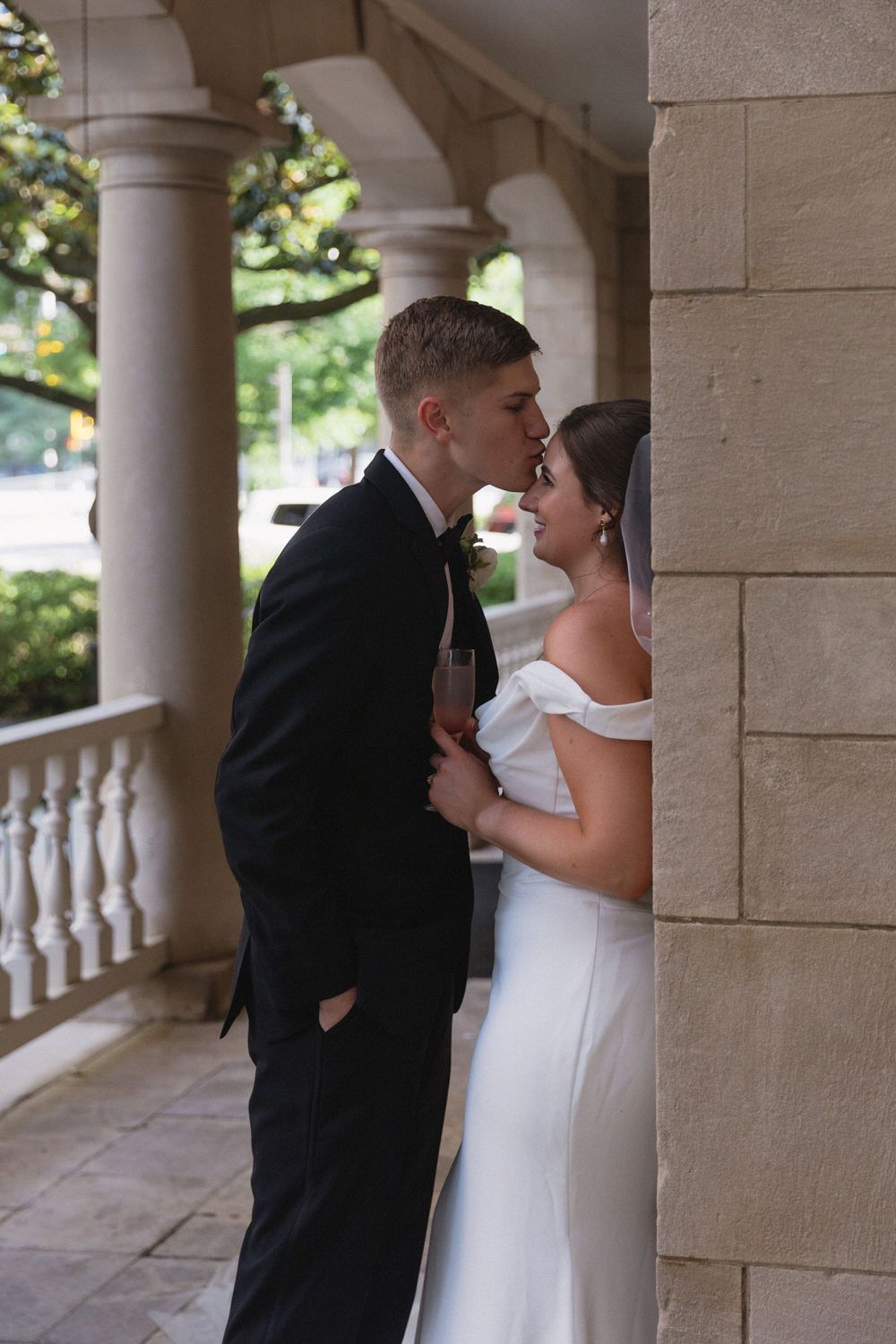 An intimate wedding moment between a couple standing beneath elegant stone columns at the wimbish house in atlanta