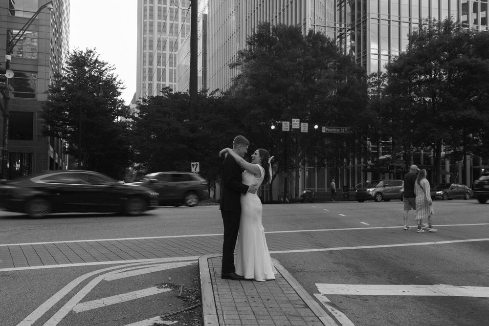 A black and white atlanta street scene with a couple embracing on a crosswalk as cars pass by during their elopement