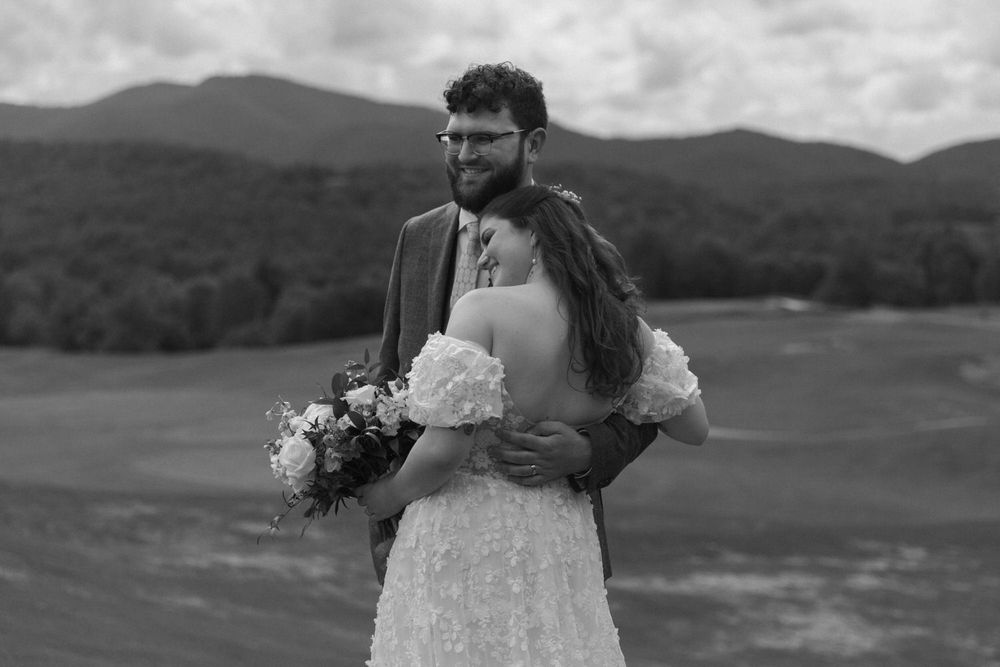 A scenic black and white mountain elopement photo showing a couple embracing outdoors with a bouquet of flowers in chattanooga