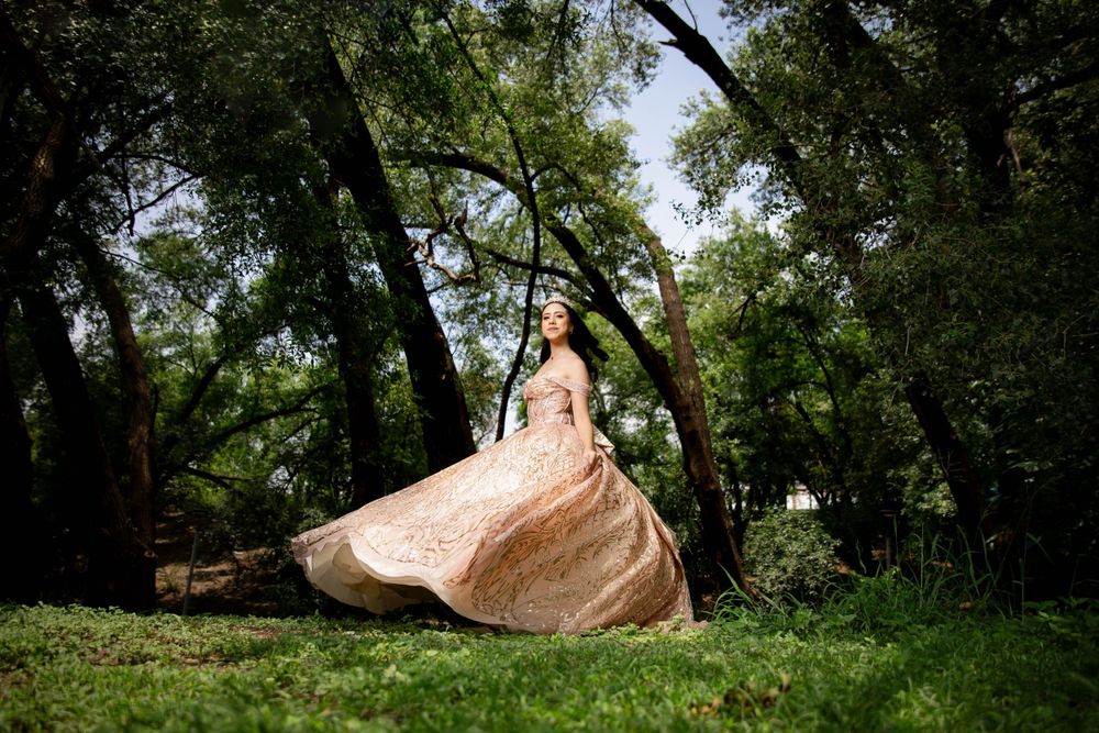 Flowing champagne-colored gown twirling in a lush forest setting.