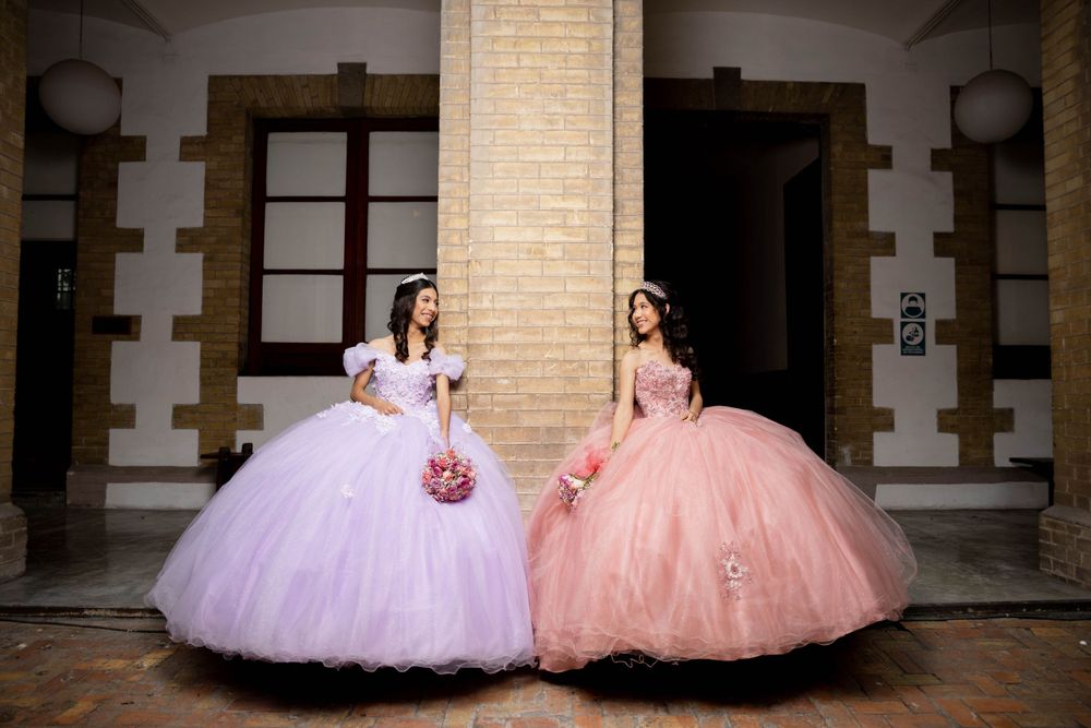 Two ball gowns in pink and lavender create a striking contrast against classic architecture.