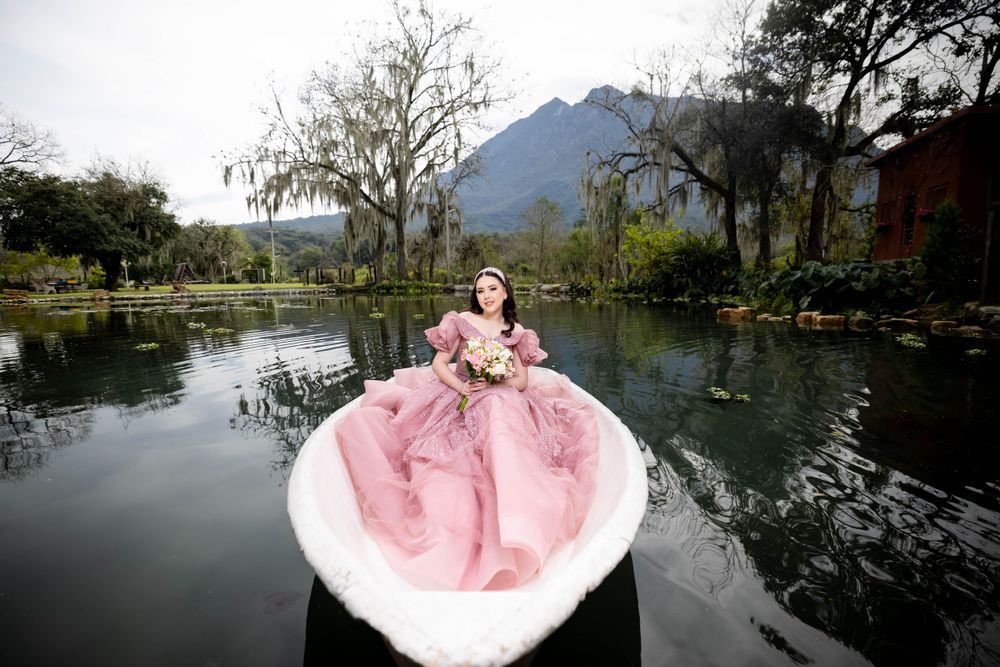 Pink ball gown photographed in a small boat on a serene lake with mountains in background.