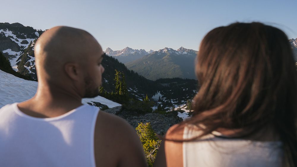 Two people looking out at mountain vistas during sunset in a scenic mountain range landscape.