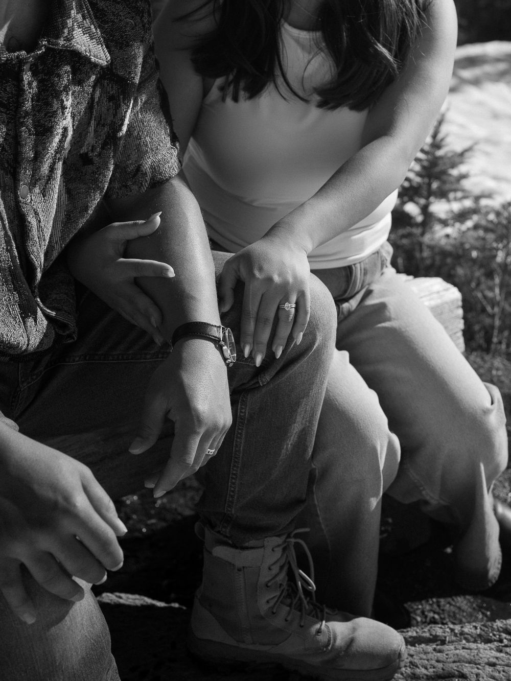 Black and white photo showing hands tying hiking boots in a casual outdoor setting.