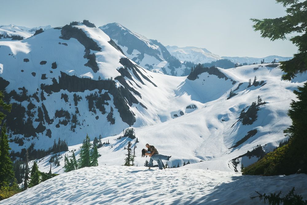 Snow-covered mountain peaks and slopes create a dramatic winter landscape in a mountain range stretching to the horizon.