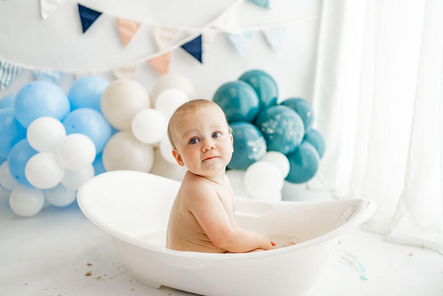 A professional photo session setup with teal and white balloons for a baby milestone or cake smash shoot.