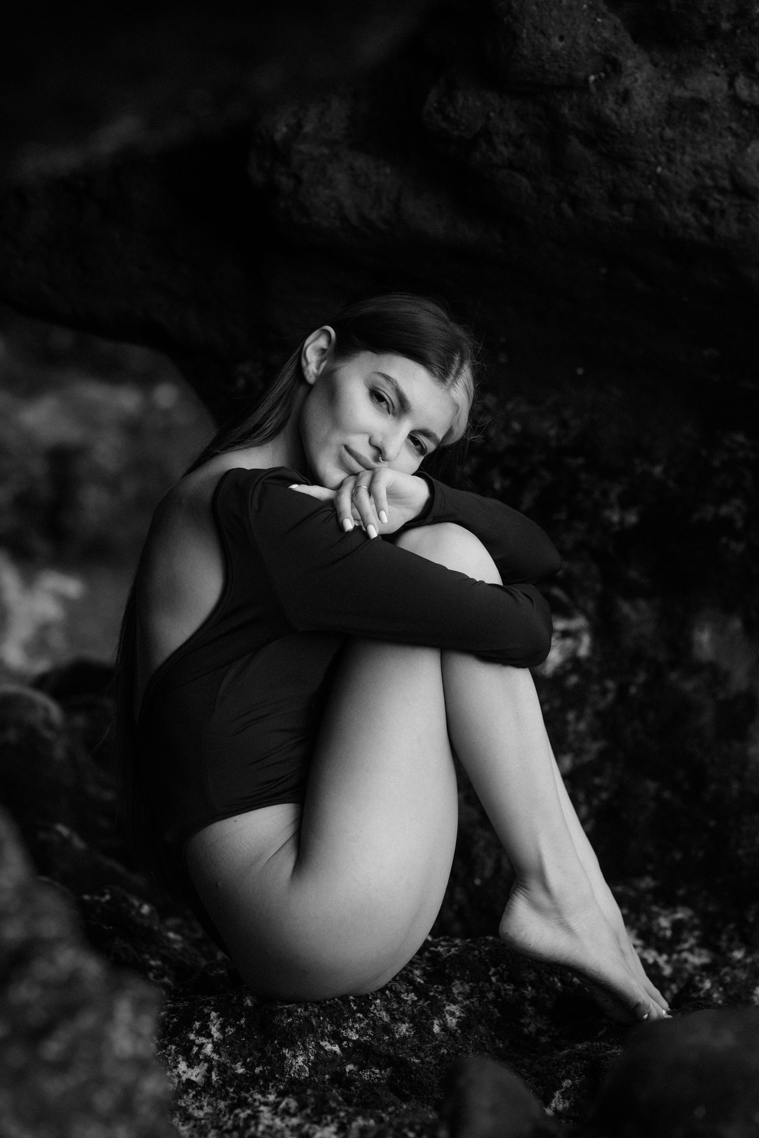 Artistic black and white portrait of a person in a leotard posing contemplatively on dark rocky terrain for a holiday photoshoot in Tenerife