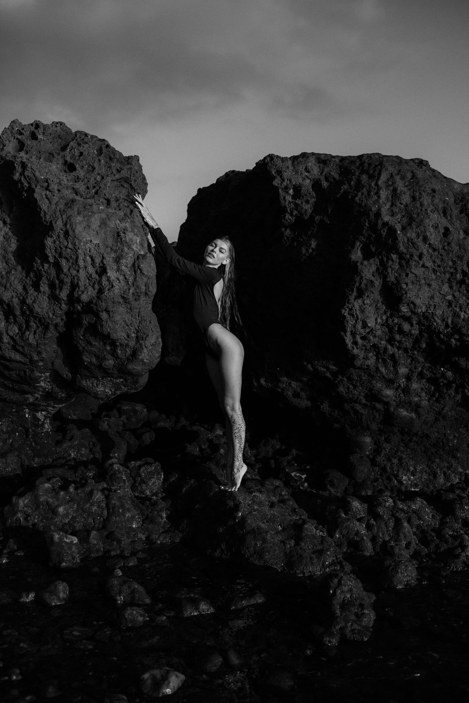 Black and white series showing a figure emerging from dark rocky formations at different angles during a vacation photoshoot in Tenerife.