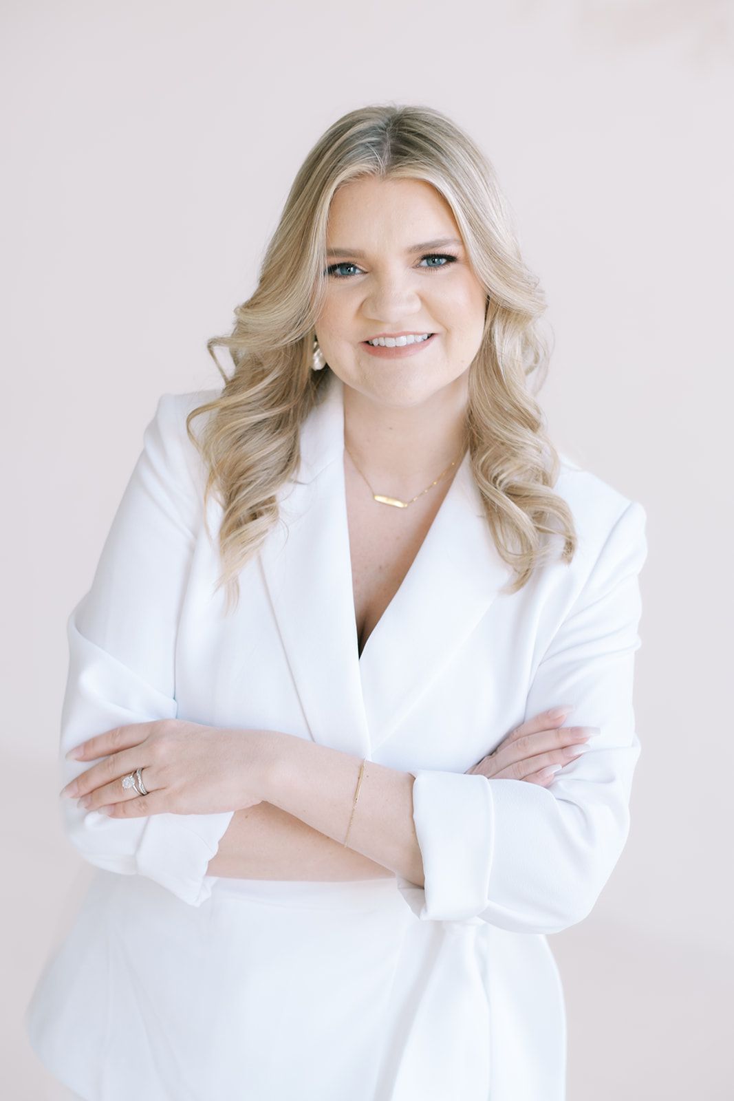 Professional portrait series featuring smiling individual in white blazer posed against light background with natural poses.