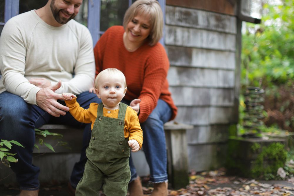 Family playing together on rustic wooden porch during casual outdoor photo session.