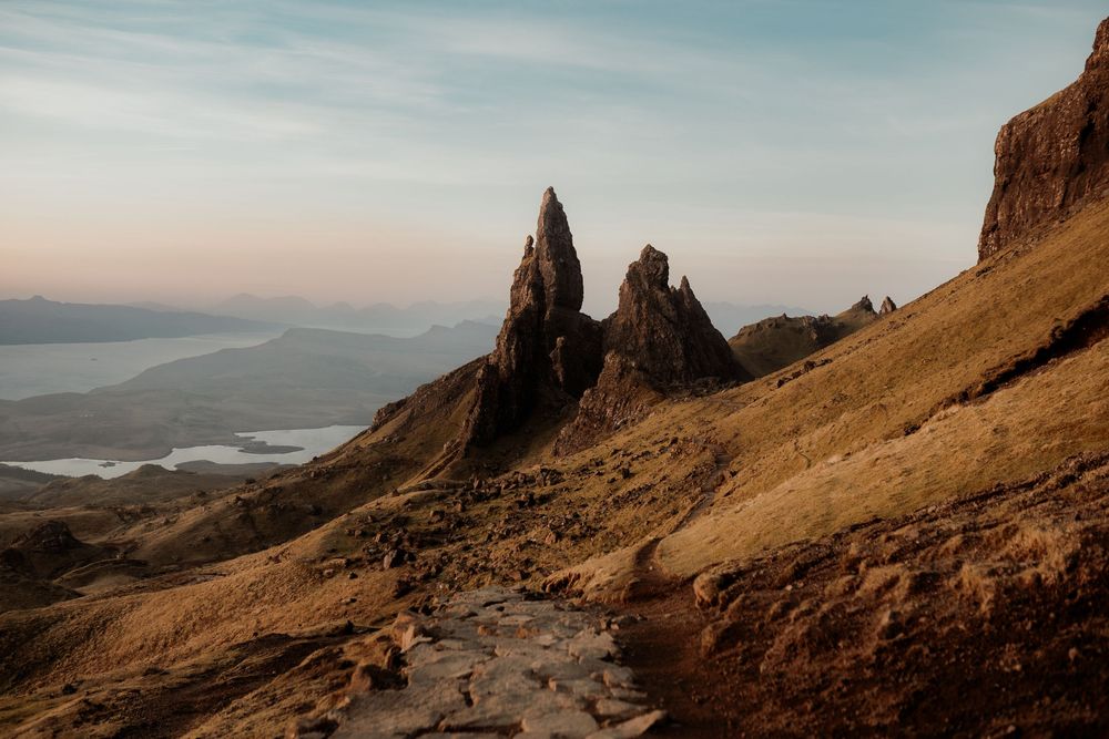 Panoramic view of rugged coastal cliffs and mountain formations along the Isle of Skye in Scotland at sunset.