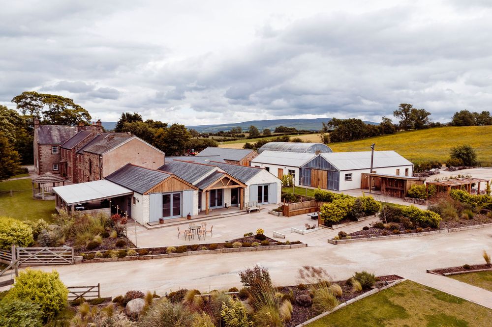 Aerial panoramic view of coastal housing development with white buildings and blue skies over rural landscape.