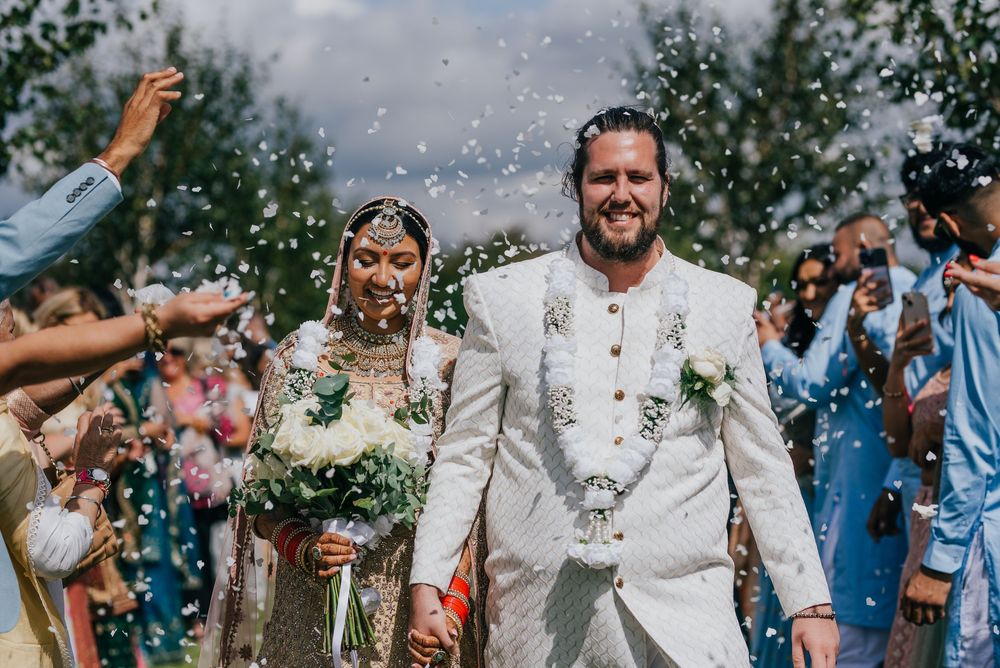 Happy couple walks together in celebration as guests toss confetti during a tropical destination wedding ceremony.