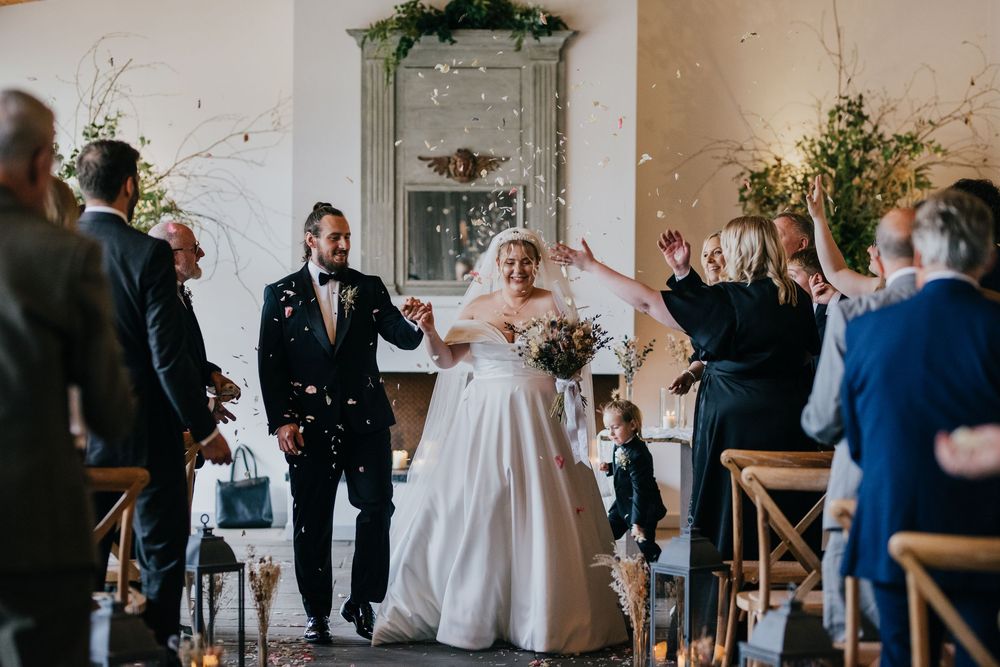 Joyful celebration at an elegant indoor wedding ceremony with floral decorations and rustic decor elements.