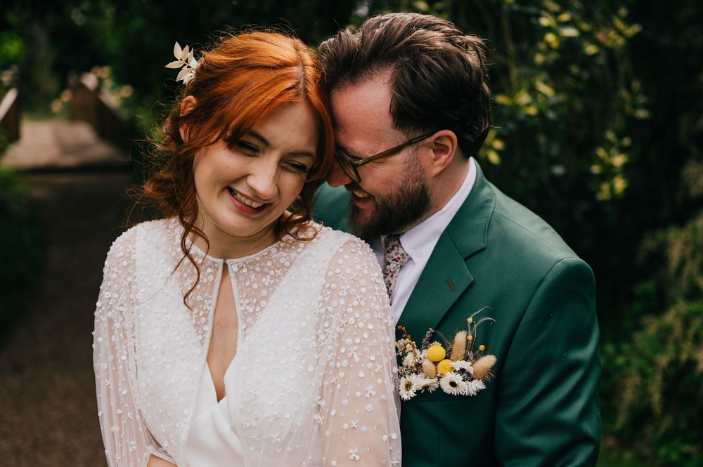A romantic wedding couple embraces in a lush garden setting with beautiful natural lighting and greenery.