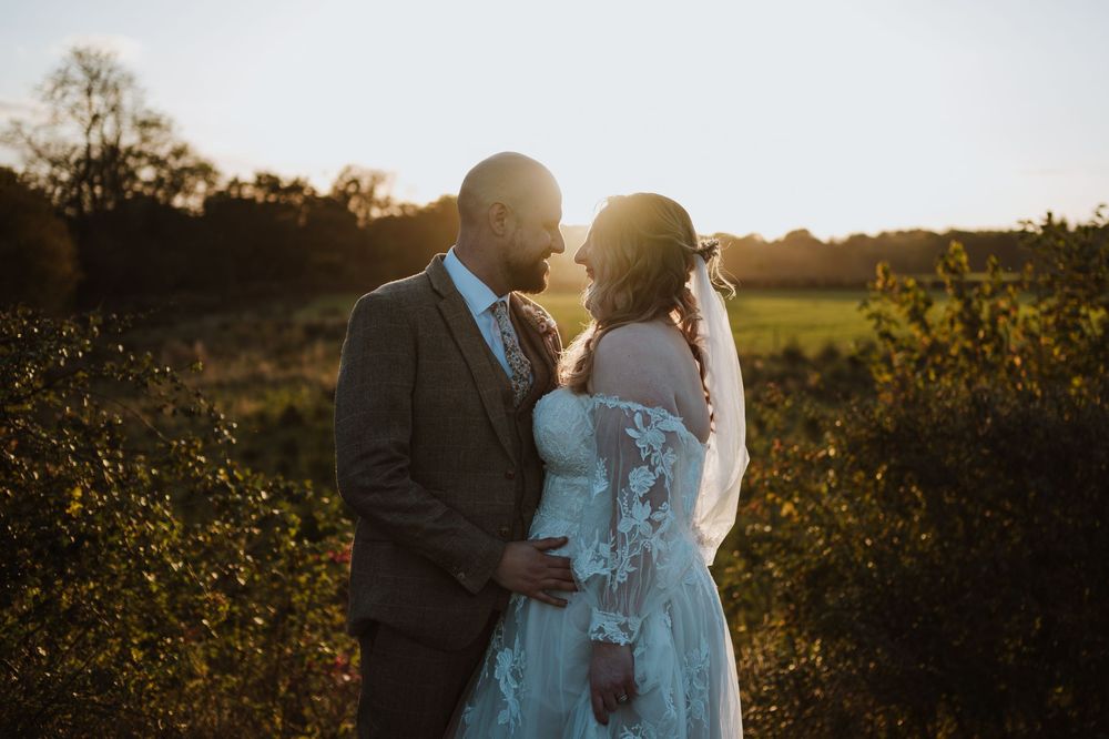 A couple shares a tender moment during golden hour in a scenic natural setting.