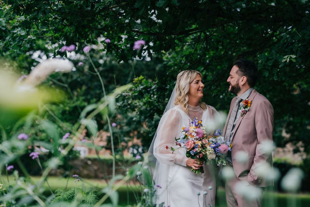 Couple shares joyful moments together in lush garden setting during wedding celebration.