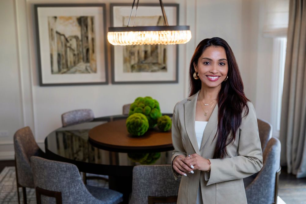 Elegant dining room features modern chandelier, moss decor, and artwork of classic European streets.