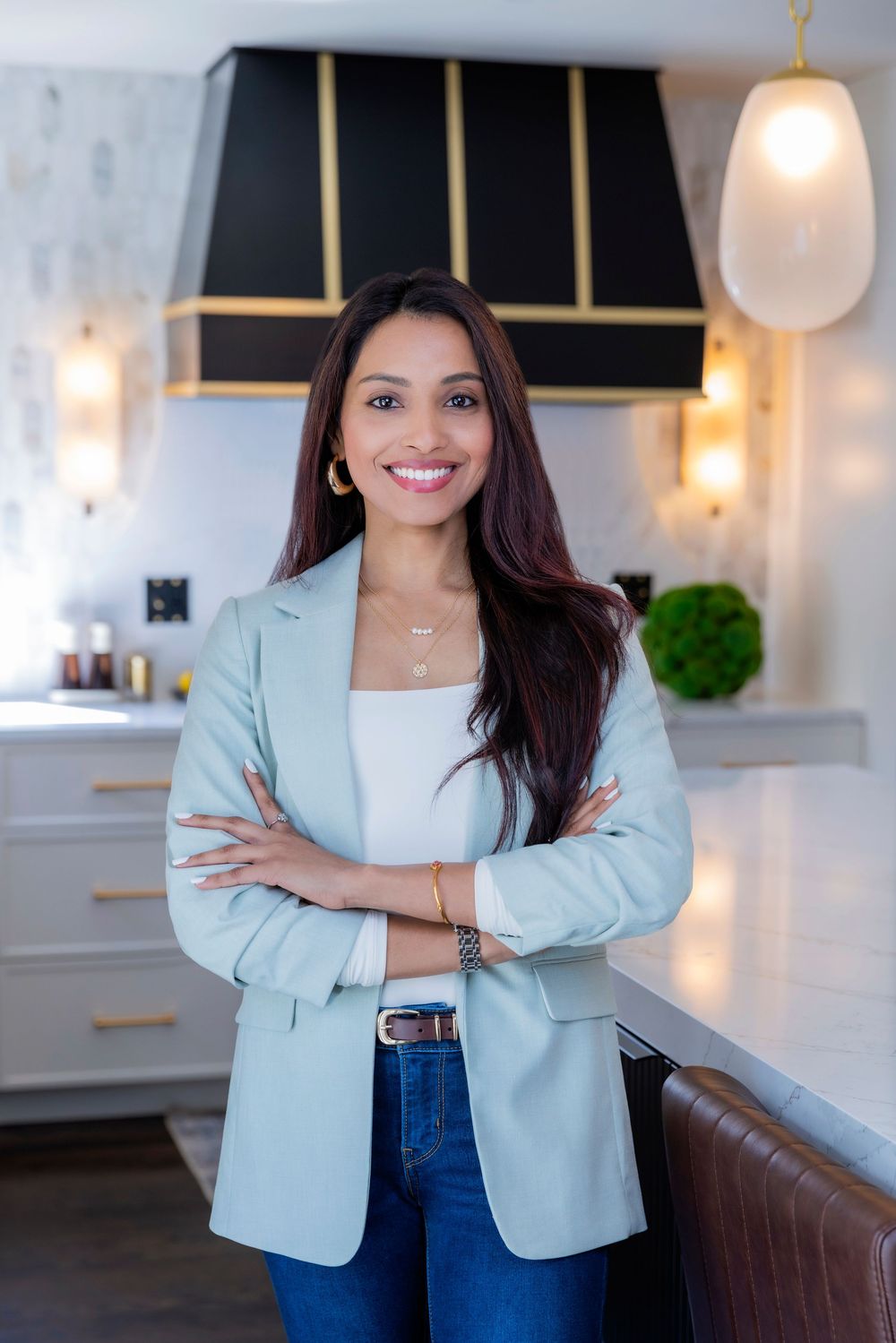 Professional headshots showing a mint blazer outfit with jeans in a modern office setting with warm lighting.