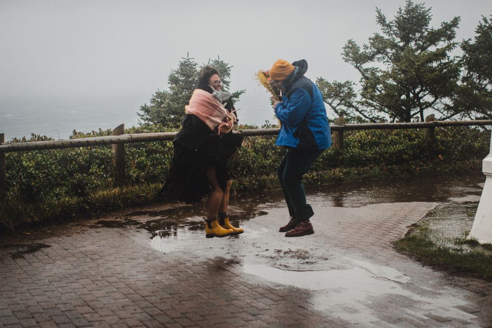 Two people dancing together on a wet pathway during a rainy day.