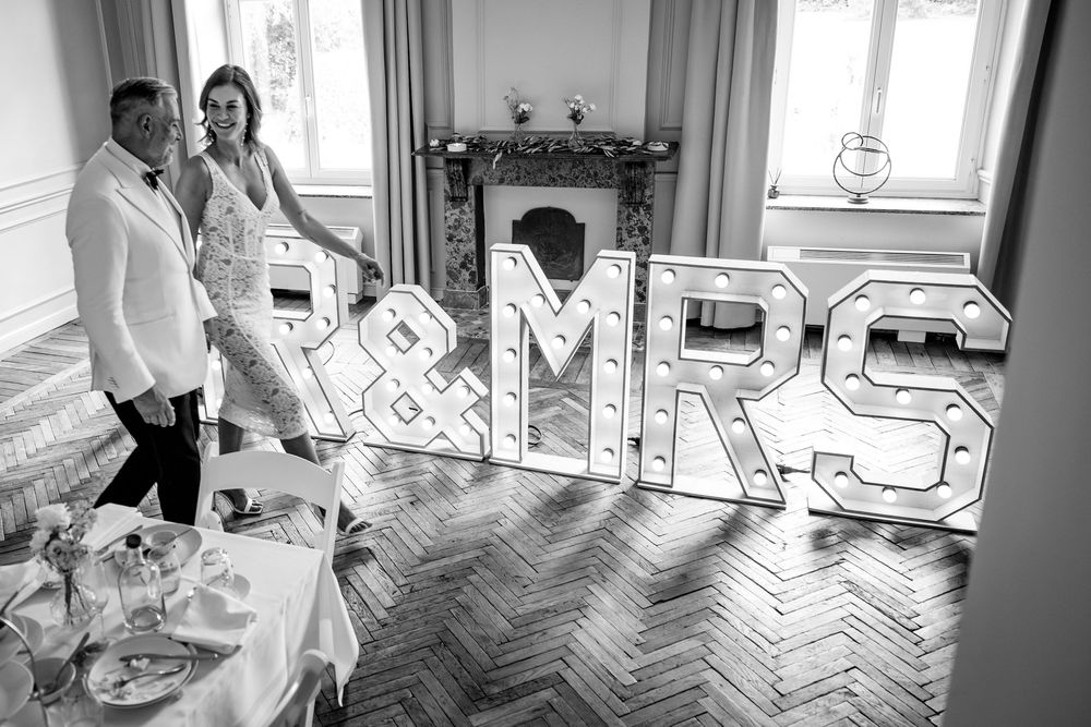 Black and white photo of a wedding reception venue with large illuminated MR & MRS letters on display.