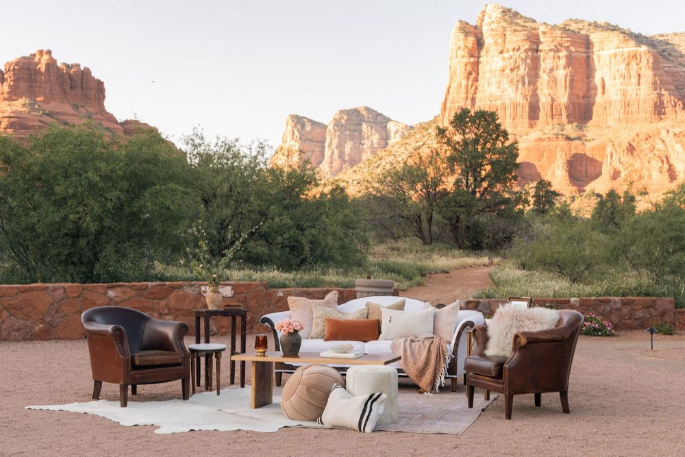 Luxurious outdoor seating area with plush chairs and cushions against dramatic red rock cliffs in Sedona.