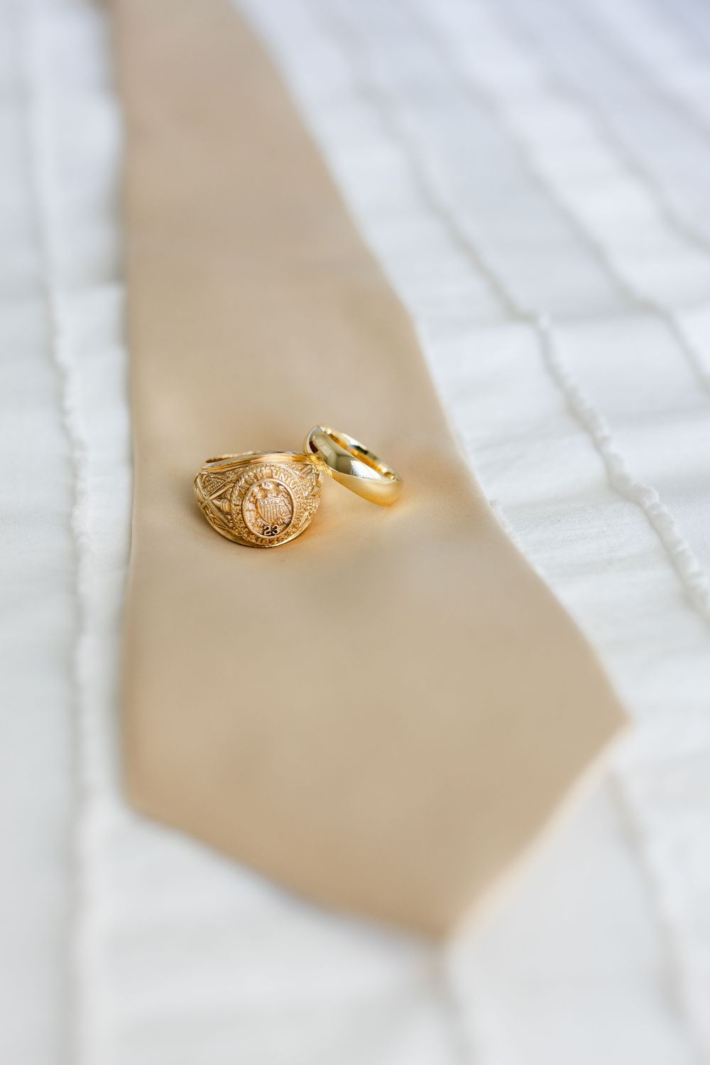 Two gold wedding rings photographed on a light beige surface with soft fabric texture.