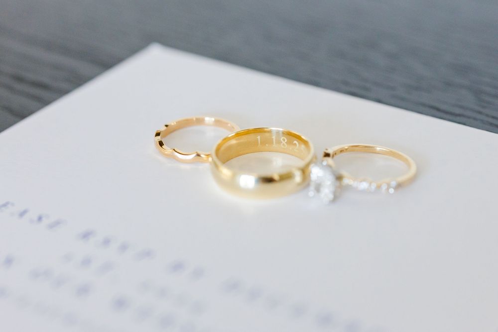 Three wedding rings including two diamond bands and one gold band arranged on a white surface.