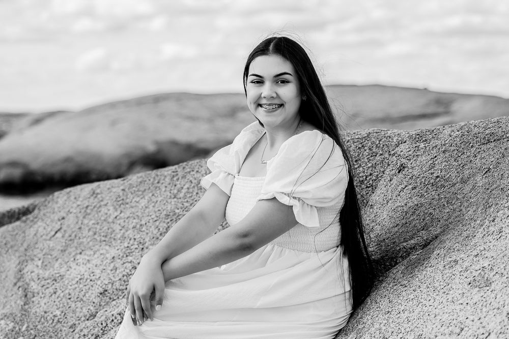 Black and white photo set showing a person in a white dress posing casually on a sandy beach at sunset.
