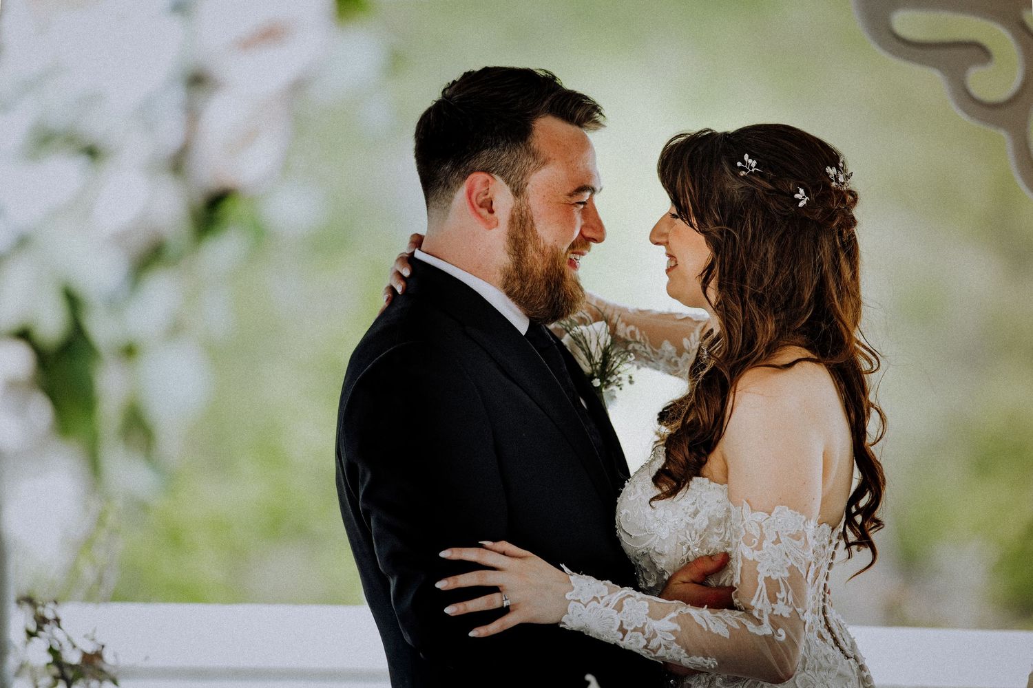 A bride and groom share an intimate moment during their wedding ceremony with soft focus nature in the background.