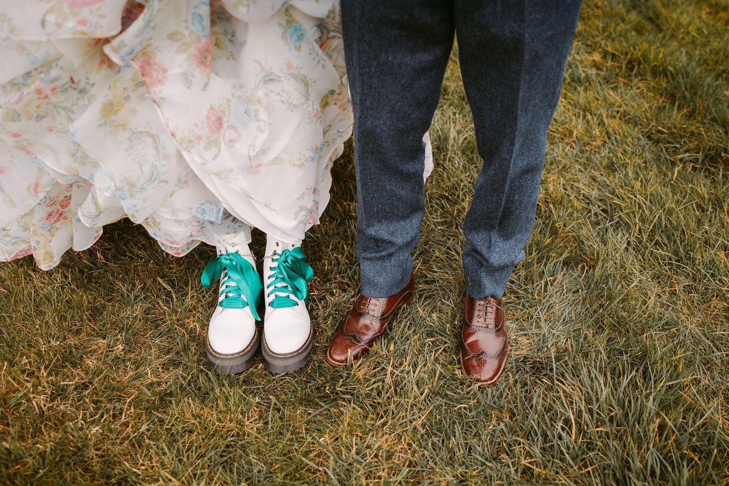 Creative wedding photo showing contrasting footwear of mint green sneakers with dress and brown leather formal shoes.