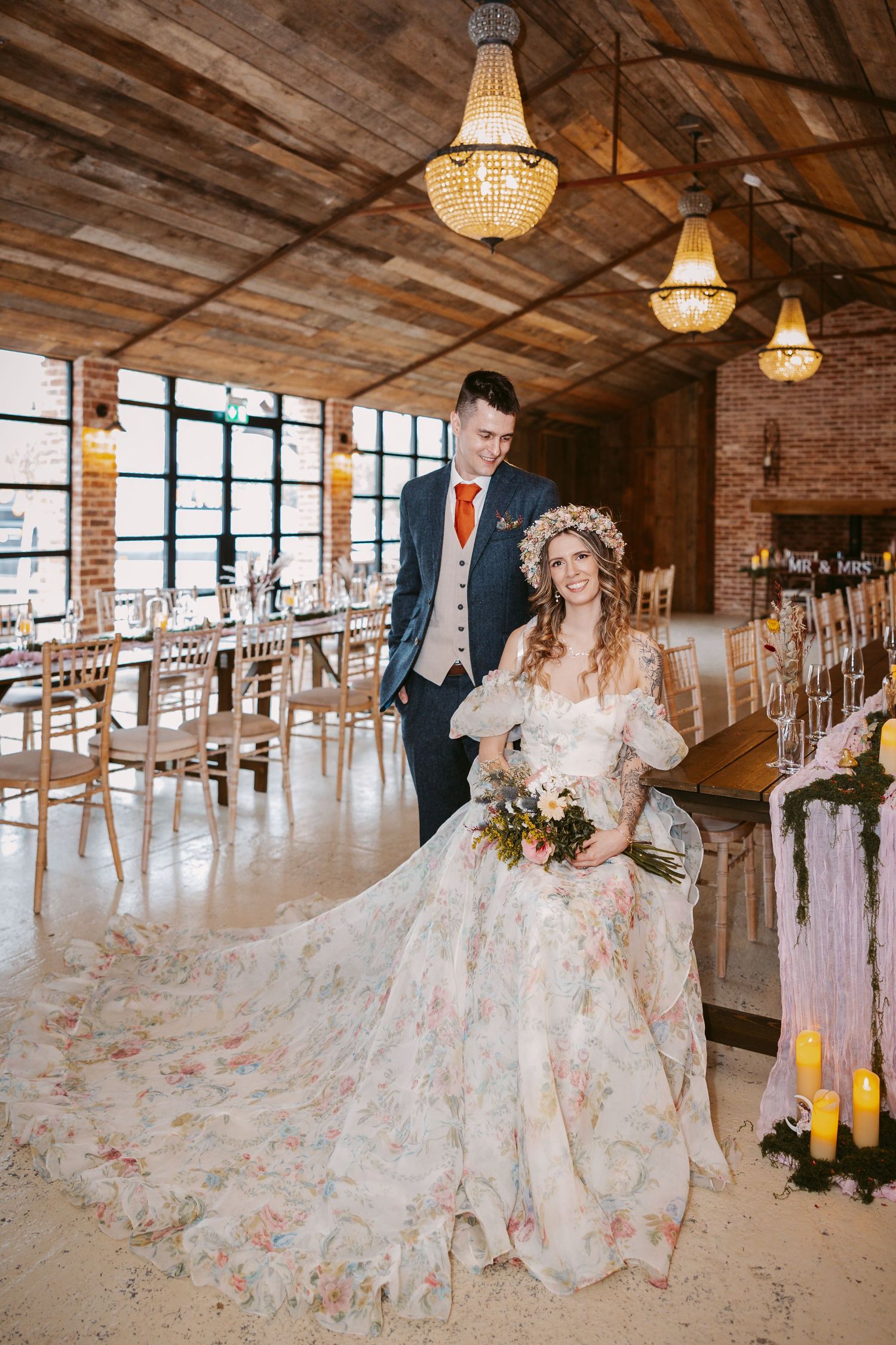 A romantic wedding celebration in a rustic wooden venue with hanging chandeliers and floral decorations.