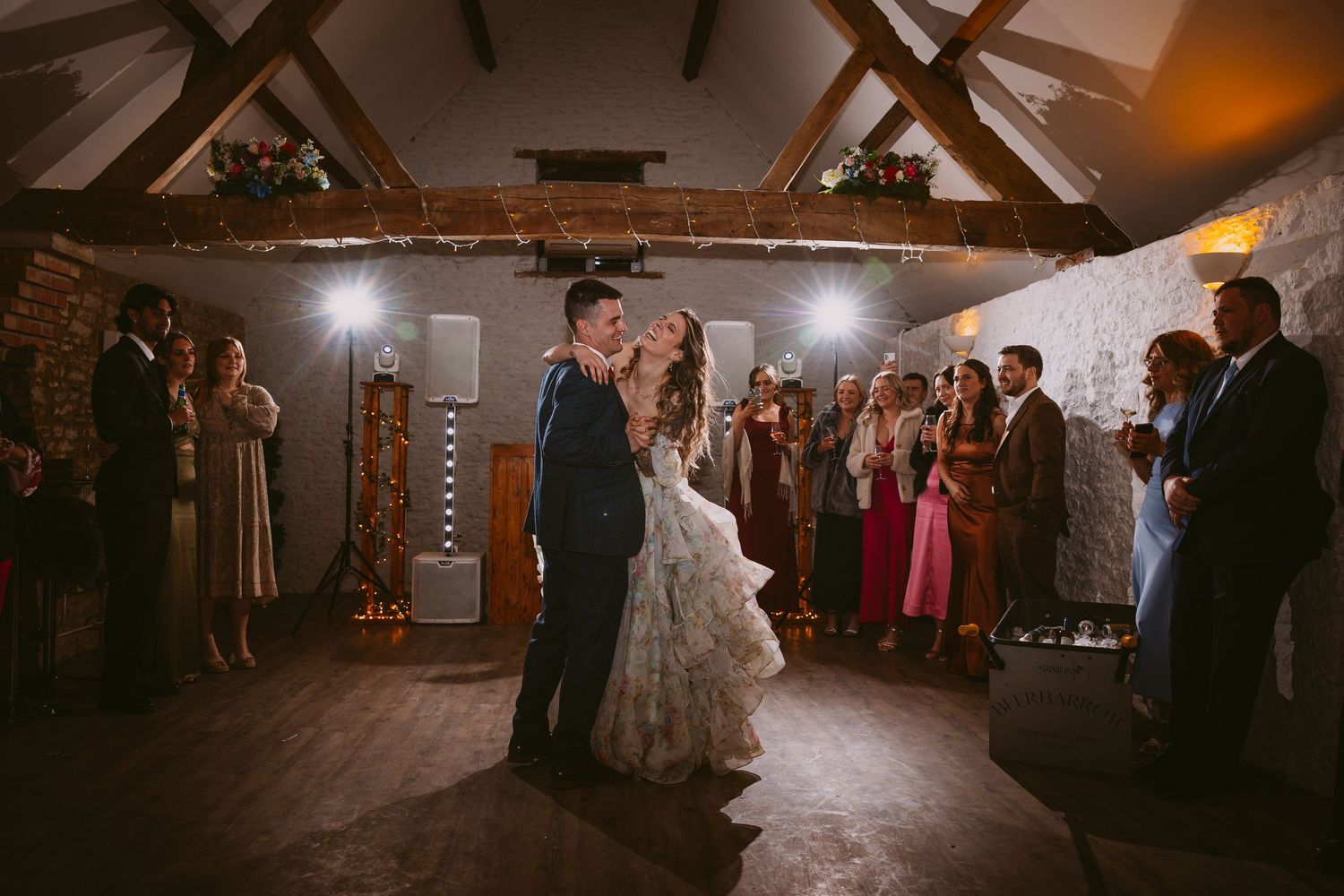 A dimly lit reception venue with warm lighting and dancing silhouettes.