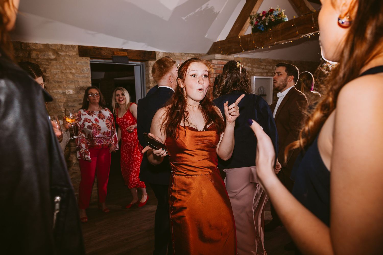 People dancing and celebrating at a festive indoor party with brick walls and atmospheric lighting.