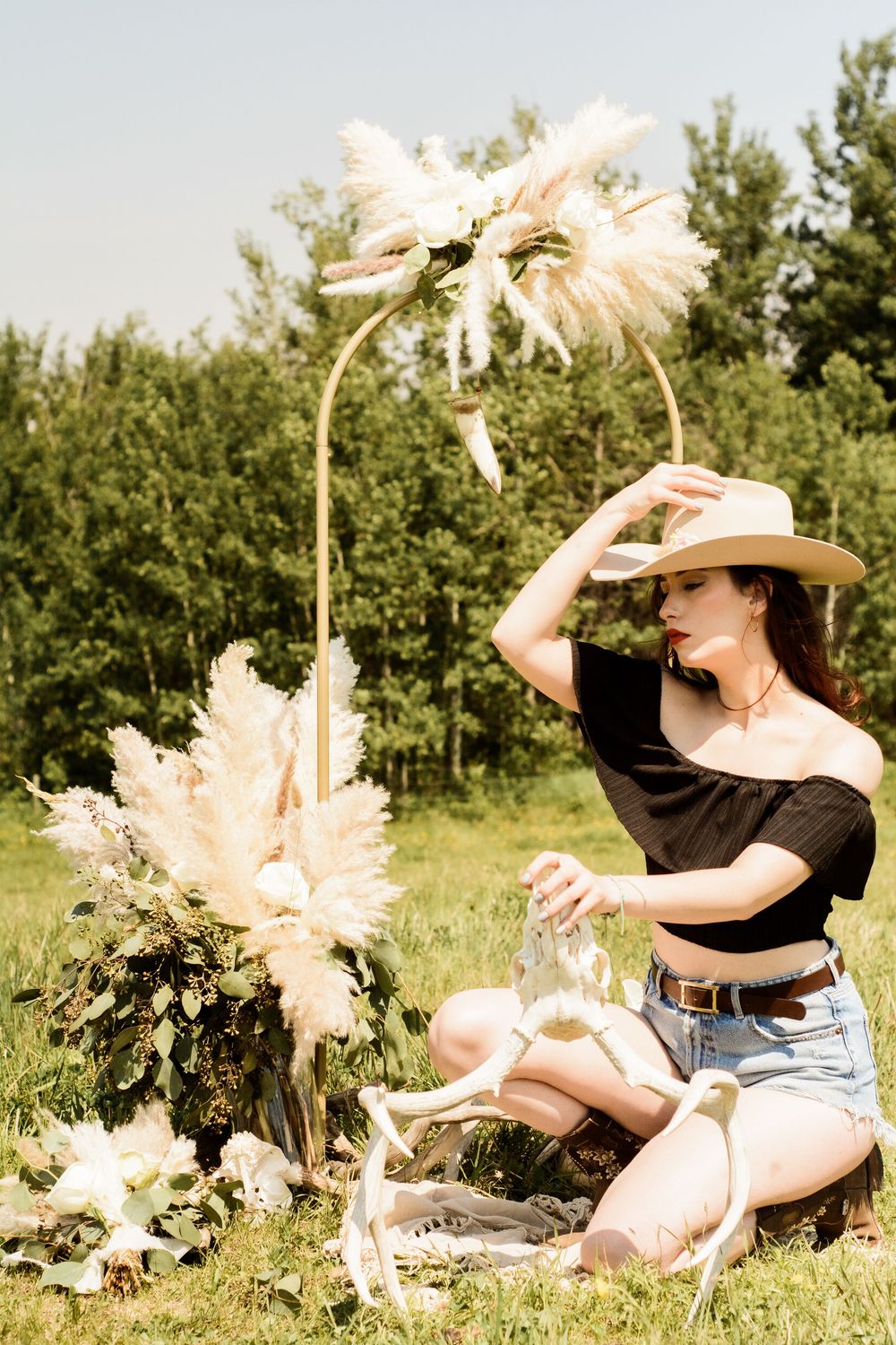 A dreamy summer scene with someone lying in a field of pampas grass and dried flowers in warm sunlight.