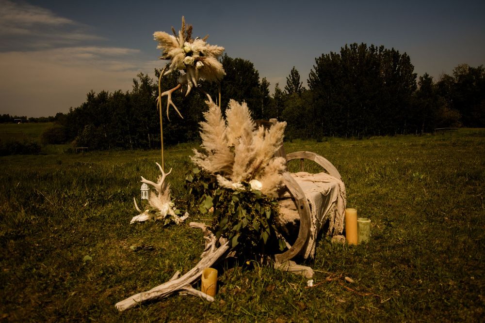 Creative floral arrangement with dried pampas grass and sunflowers displayed on rustic wood in a field at sunset.